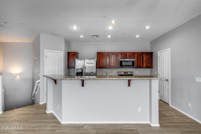 2941 E Darrow St, Phoenix, AZ 85042 - kitchen featuring stainless steel appliances, light wood finished floors, a kitchen breakfast bar, recessed lighting, and light stone countertops