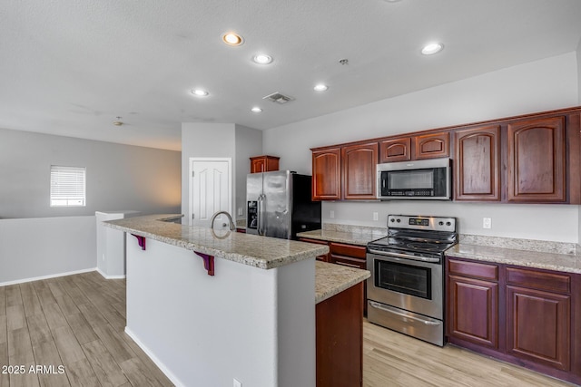 2941 E Darrow St, Phoenix, AZ 85042 - kitchen featuring appliances with stainless steel finishes, light wood-style flooring, a center island with sink, recessed lighting, and a kitchen breakfast bar