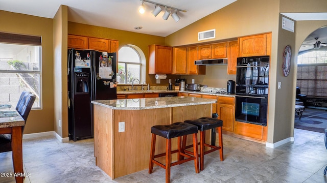 10952 S Desert Lake Dr, Goodyear, AZ 85338 - kitchen with visible vents, a kitchen island, under cabinet range hood, black appliances, and vaulted ceiling