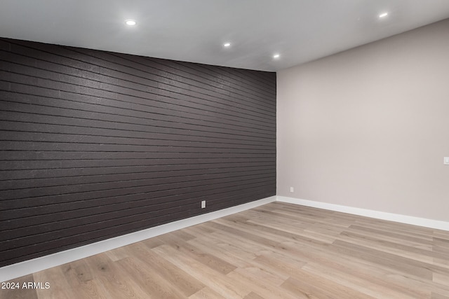 spare room featuring light wood-type flooring and wooden walls