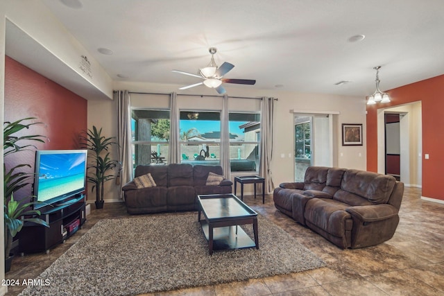 tiled living room with ceiling fan with notable chandelier