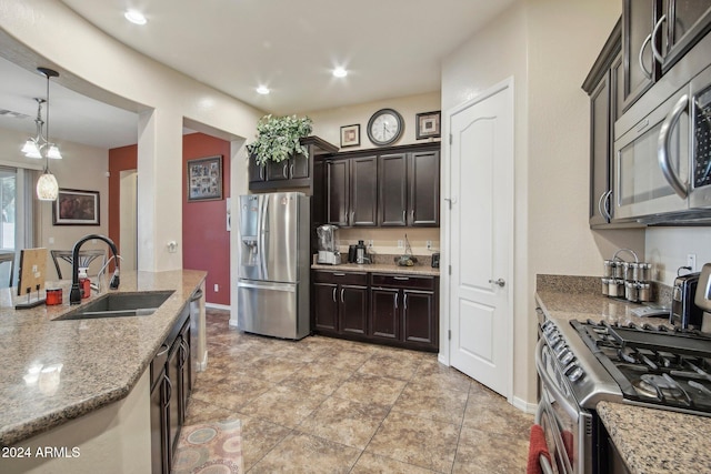 kitchen with sink, light stone counters, decorative light fixtures, dark brown cabinets, and appliances with stainless steel finishes