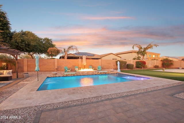 pool at dusk featuring a patio area and pool water feature