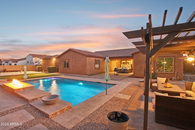 pool at dusk with a pergola, an outdoor living space with a fire pit, and a patio area