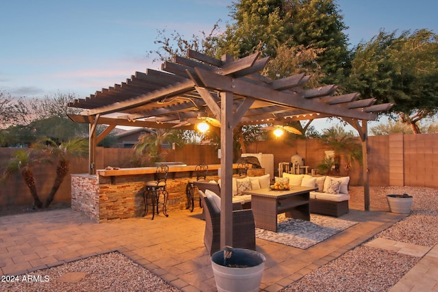 patio terrace at dusk with outdoor lounge area, a pergola, and an outdoor bar