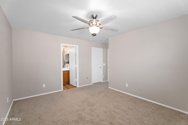 unfurnished bedroom with baseboards, ceiling fan, ensuite bathroom, and light colored carpet