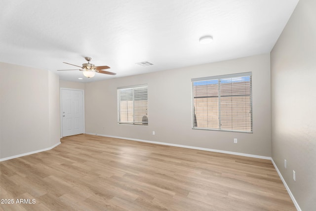 unfurnished room featuring light wood-type flooring, a healthy amount of sunlight, visible vents, and baseboards