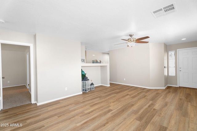 unfurnished living room featuring a ceiling fan, visible vents, baseboards, and wood finished floors