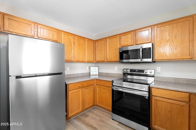 kitchen with appliances with stainless steel finishes, light countertops, and light wood-style flooring