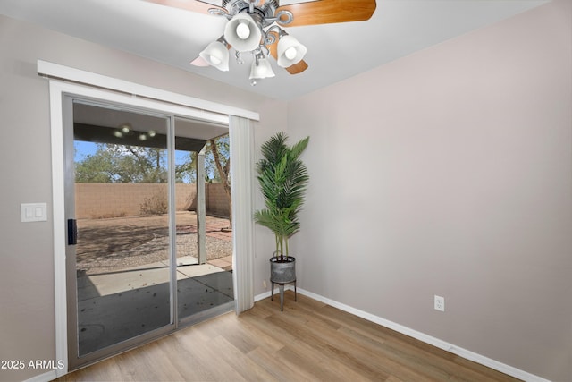 spare room with light wood finished floors, ceiling fan, and baseboards