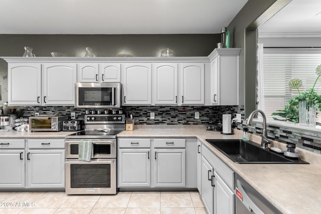 kitchen with sink, white cabinets, stainless steel appliances, and light tile patterned floors