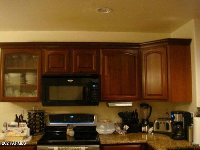 kitchen featuring dark stone counters and black appliances