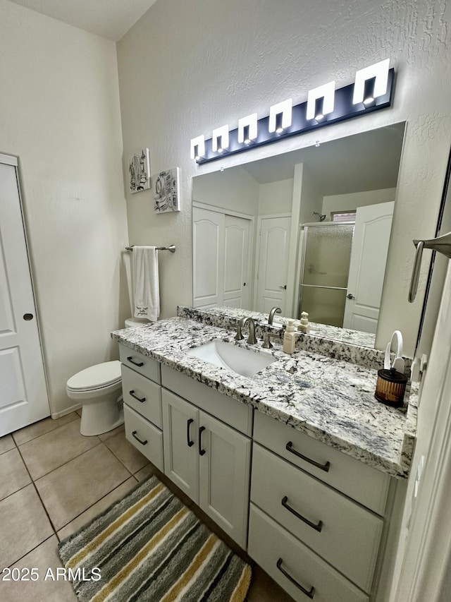 full bath featuring vanity, tile patterned flooring, a shower stall, toilet, and a textured wall