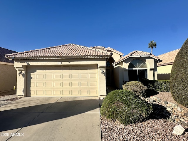 view of front facade with a tile roof, a garage, driveway, and stucco siding