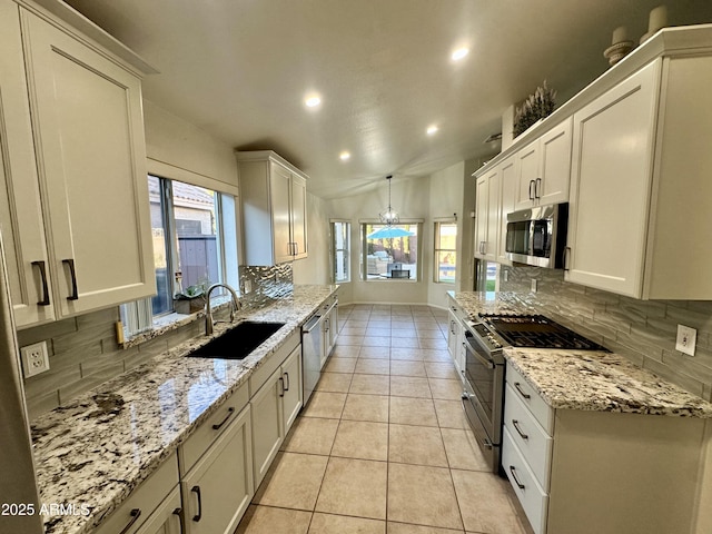 kitchen featuring a sink, light stone counters, backsplash, stainless steel appliances, and light tile patterned flooring