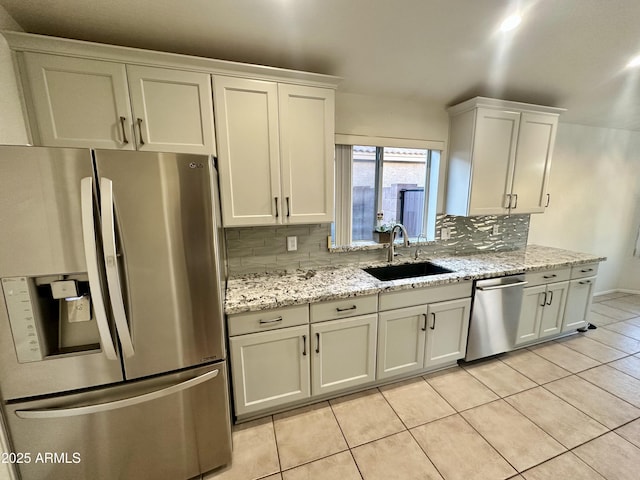 kitchen with backsplash, light stone counters, appliances with stainless steel finishes, light tile patterned flooring, and a sink