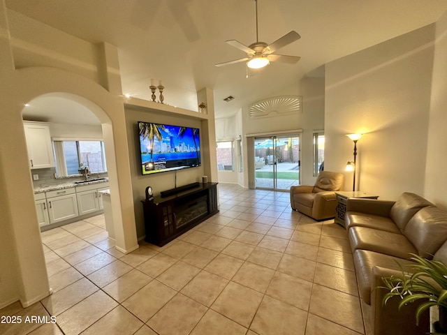 living room featuring light tile patterned floors, visible vents, arched walkways, and a ceiling fan