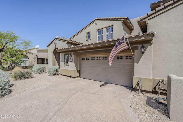 mediterranean / spanish-style home featuring a tile roof, stucco siding, a garage, and driveway