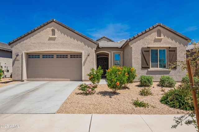 view of front of home with a garage, stucco siding, driveway, and a tile roof
