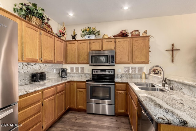 kitchen with dark hardwood / wood-style flooring, light stone countertops, sink, and appliances with stainless steel finishes