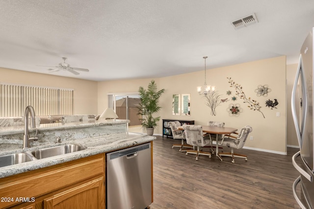 kitchen with appliances with stainless steel finishes, ceiling fan with notable chandelier, dark wood-type flooring, sink, and pendant lighting