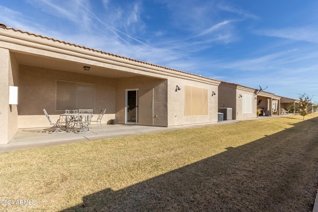 back of property with a yard, a patio, and central air condition unit