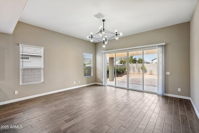 empty room with an inviting chandelier, a wealth of natural light, and dark hardwood / wood-style flooring