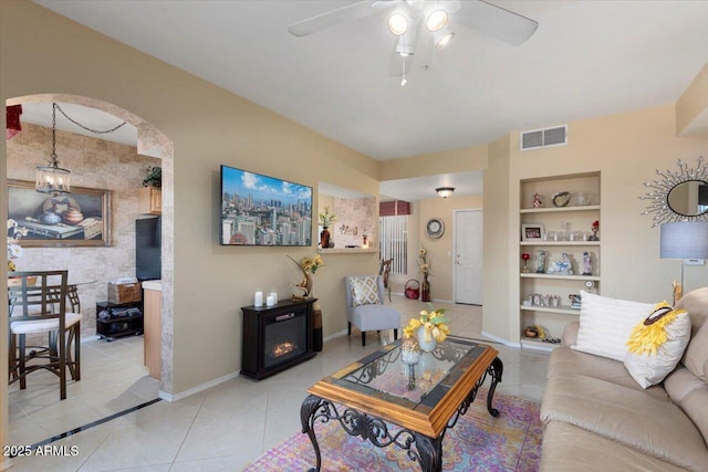 tiled living room with ceiling fan and built in shelves