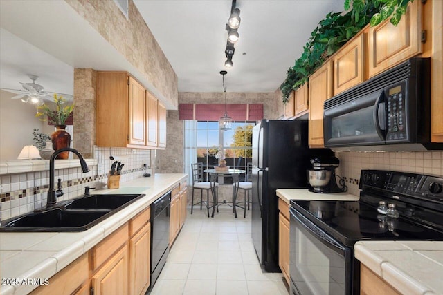 kitchen featuring tile counters, black appliances, pendant lighting, sink, and tasteful backsplash