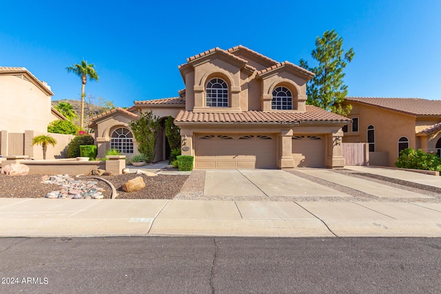 mediterranean / spanish-style house featuring stucco siding, concrete driveway, an attached garage, and a tile roof