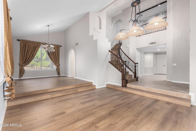 foyer featuring a chandelier, high vaulted ceiling, stairs, baseboards, and arched walkways
