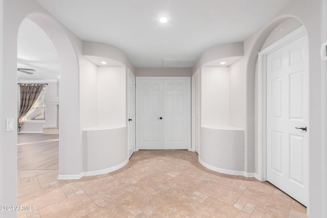 hallway with arched walkways, baseboards, and recessed lighting
