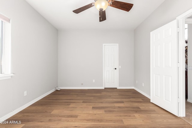 empty room with ceiling fan, wood finished floors, and baseboards