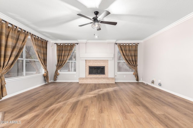 unfurnished living room with a ceiling fan, baseboards, wood finished floors, a high end fireplace, and crown molding