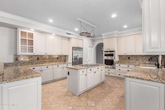 kitchen with stainless steel appliances, a sink, ornamental molding, arched walkways, and recessed lighting