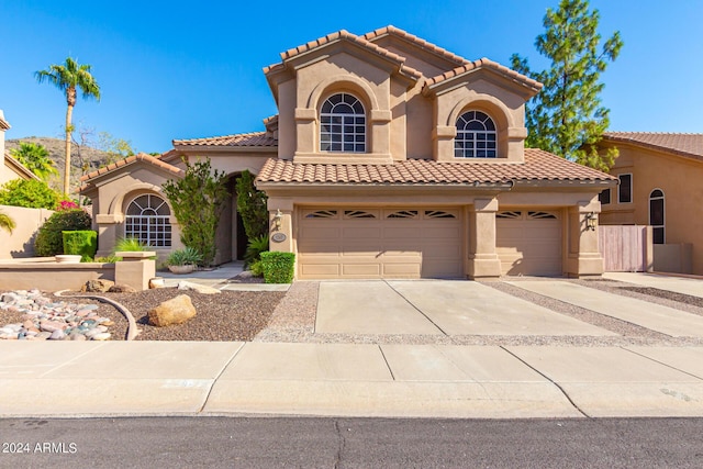 mediterranean / spanish-style home with stucco siding, concrete driveway, an attached garage, and a tiled roof