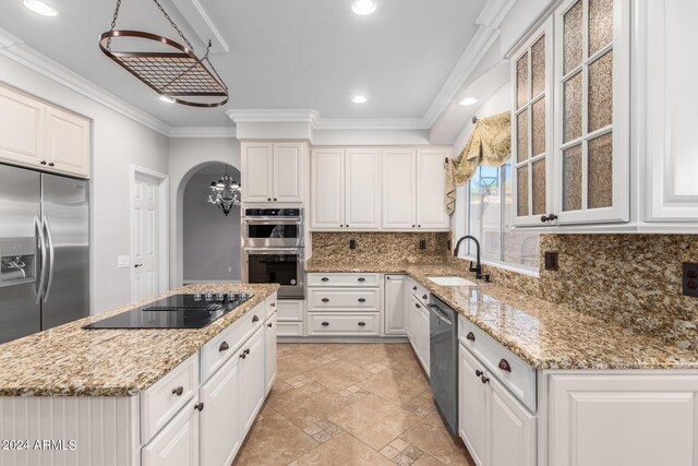 kitchen with a sink, stainless steel appliances, ornamental molding, decorative backsplash, and a center island