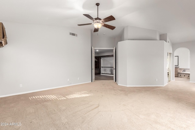 unfurnished living room with light colored carpet, arched walkways, ceiling fan, baseboards, and lofted ceiling