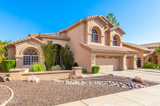 mediterranean / spanish-style house with a tiled roof, stucco siding, concrete driveway, and a garage