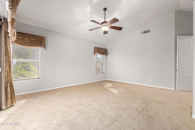 spare room featuring vaulted ceiling, light colored carpet, ceiling fan, and baseboards