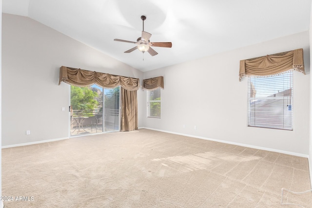 empty room featuring lofted ceiling, ceiling fan, carpet, and baseboards