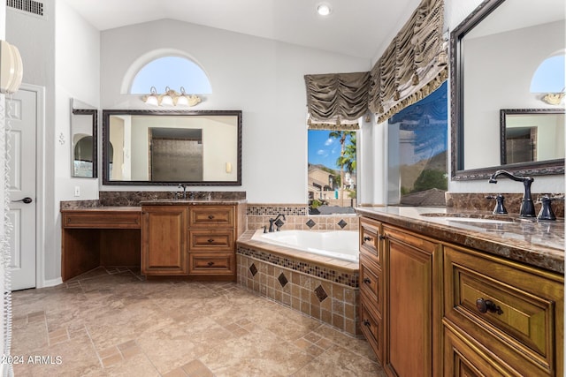full bath featuring vaulted ceiling, a garden tub, two vanities, and stone finish floors