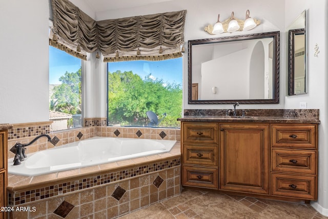 bathroom with a garden tub, plenty of natural light, and vanity