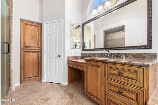 full bath with baseboards, vanity, a shower with door, and stone finish floors