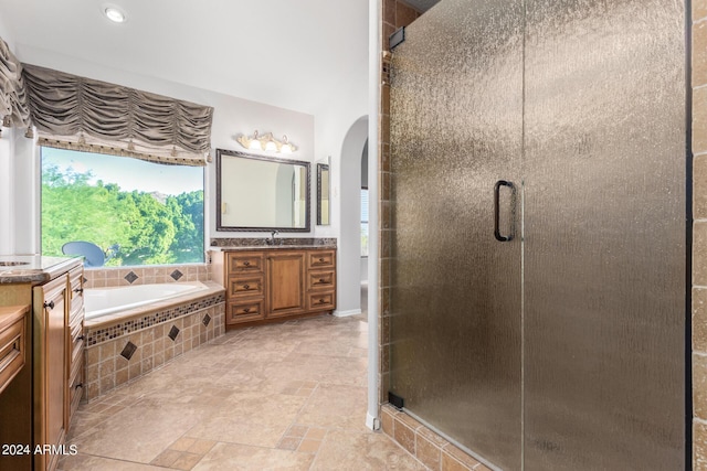 bathroom with a stall shower, vanity, a garden tub, and stone finish flooring