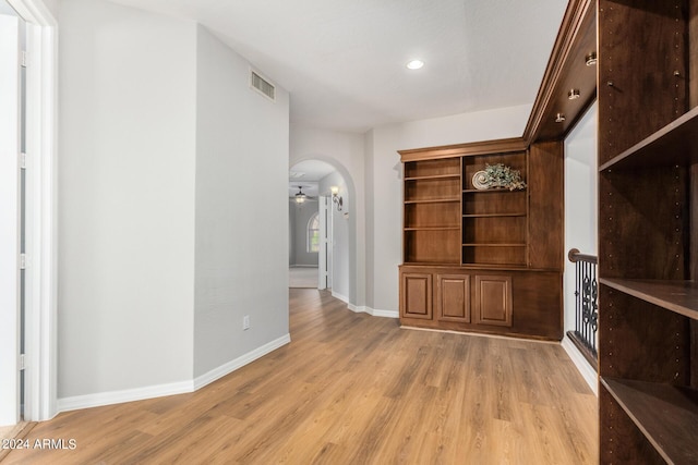 unfurnished dining area featuring arched walkways, light wood-style flooring, baseboards, and recessed lighting