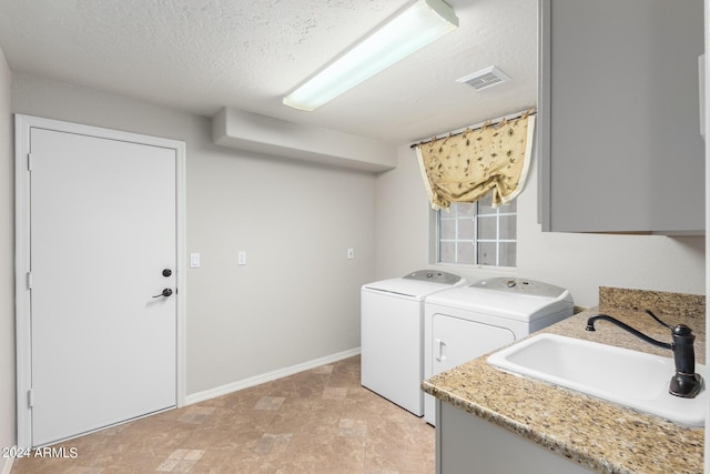 laundry room featuring washing machine and dryer, a sink, baseboards, and a textured ceiling