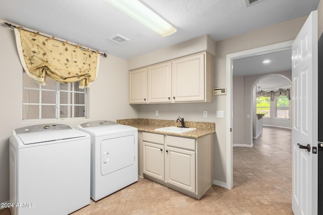 laundry area featuring independent washer and dryer, cabinet space, arched walkways, and baseboards