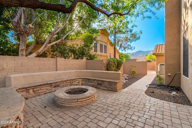 view of patio with a fire pit, a fenced backyard, central AC, and a mountain view