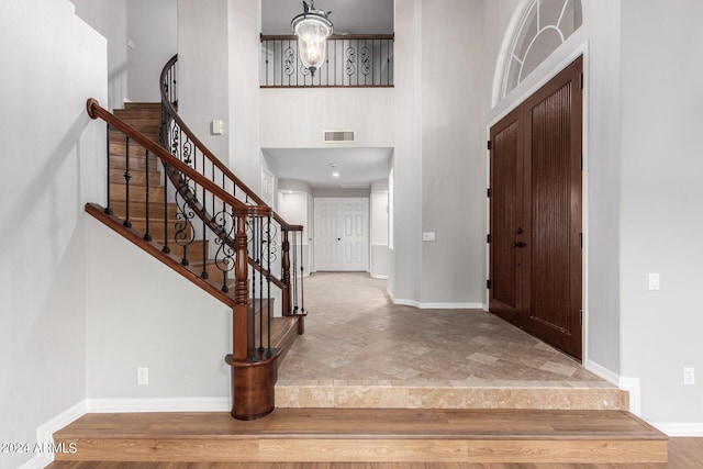 entrance foyer with stairway, a towering ceiling, and baseboards